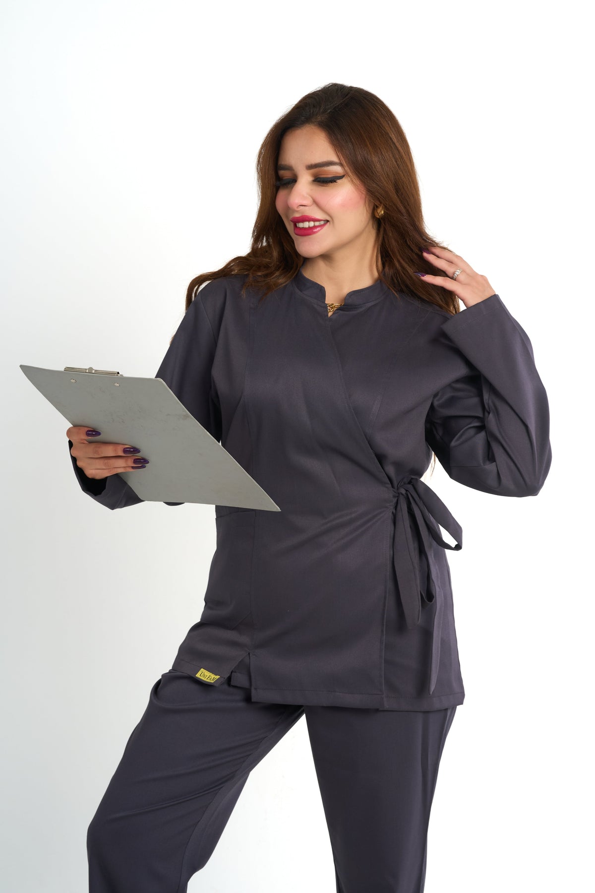 A woman modeling a white long lab coat over a black V-neck top and black pants, standing against a plain white studio background.